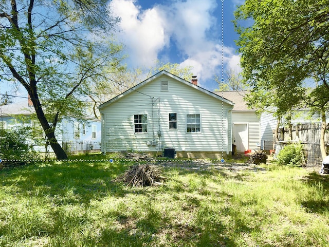 back of property with central AC, fence, and a chimney