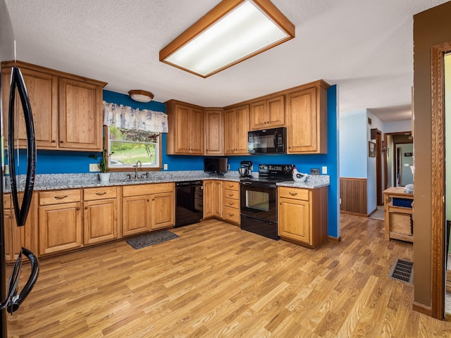 1305 Cooperriders Rd NW, Somerset, OH 43783 - kitchen with a sink, light wood finished floors, brown cabinetry, visible vents, and black appliances