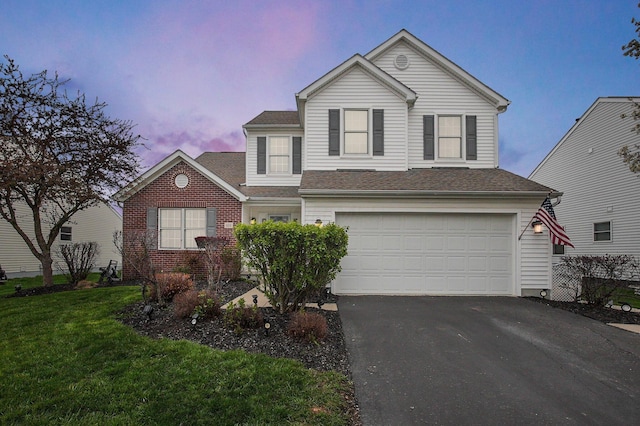 traditional home with a shingled roof, a front lawn, brick siding, a garage, and aphalt driveway
