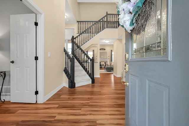 foyer entrance featuring a high ceiling, baseboards, wood finished floors, and stairway