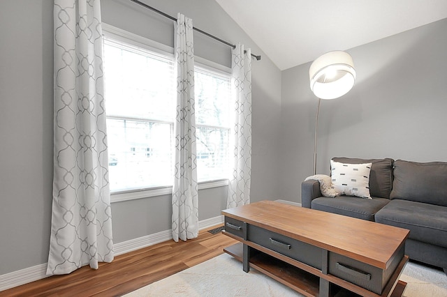 living area featuring baseboards, visible vents, wood finished floors, and lofted ceiling
