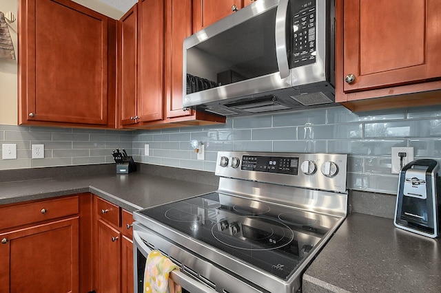 kitchen featuring backsplash, brown cabinets, dark countertops, and stainless steel appliances