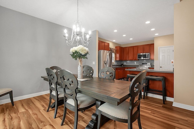 dining space with an inviting chandelier, light wood-style flooring, baseboards, and recessed lighting