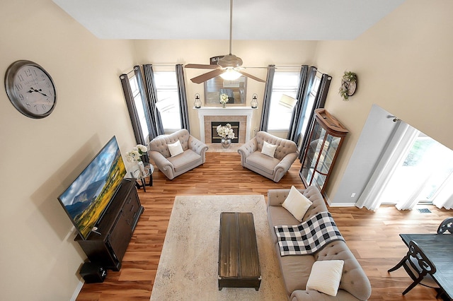 living room featuring baseboards, ceiling fan, a healthy amount of sunlight, and wood finished floors
