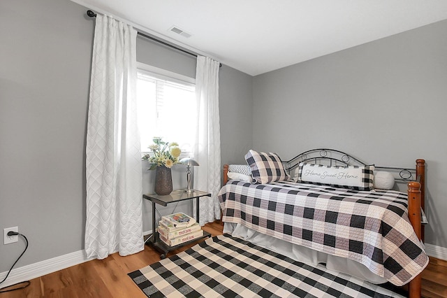 bedroom with baseboards, wood finished floors, and visible vents