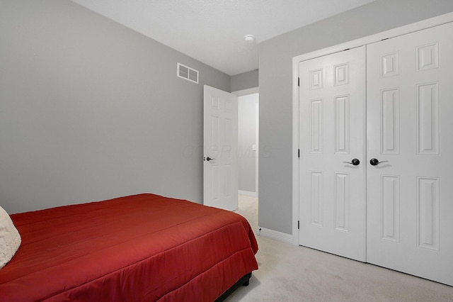 bedroom with light colored carpet, baseboards, visible vents, and a closet