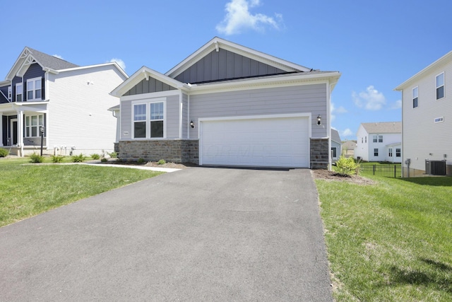 craftsman-style home featuring a front yard, stone siding, board and batten siding, central air condition unit, and driveway