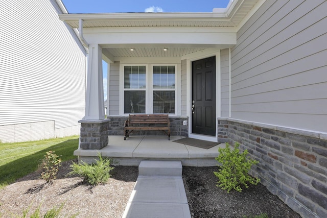 property entrance featuring a porch and stone siding