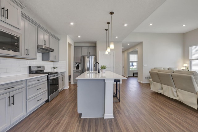 kitchen featuring stainless steel appliances, open floor plan, gray cabinetry, and dark wood finished floors