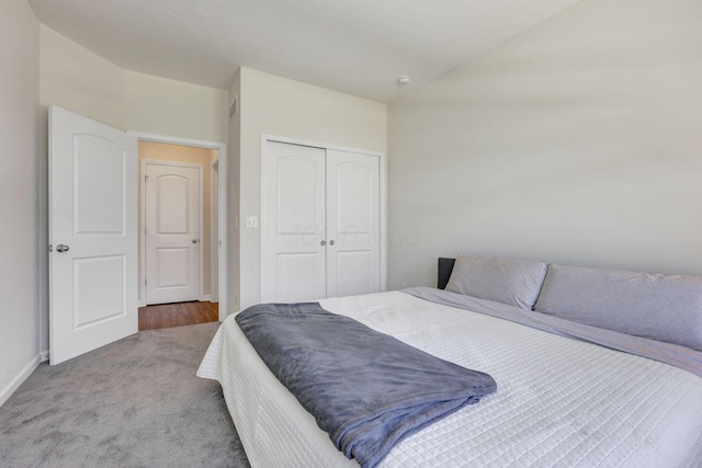 carpeted bedroom with baseboards, a closet, and lofted ceiling