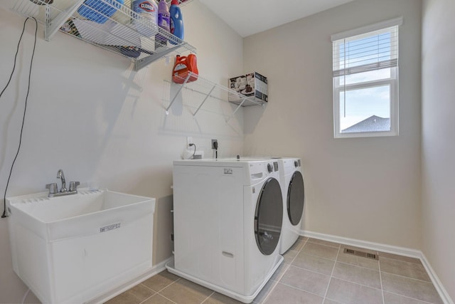 clothes washing area with laundry area, visible vents, baseboards, separate washer and dryer, and a sink