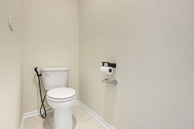 half bathroom featuring toilet, baseboards, and marble finish floor