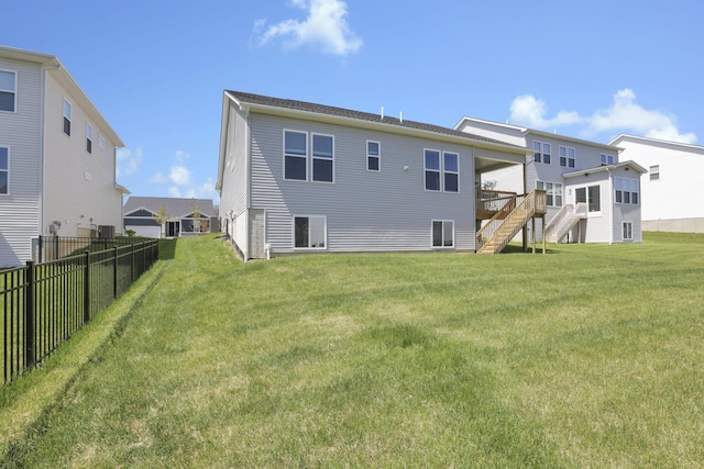 rear view of property featuring stairway, a deck, a yard, and fence