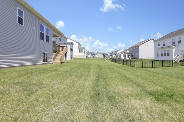 view of yard featuring fence, a residential view, stairs, and a wooden deck