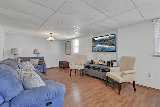 living room featuring baseboards, a paneled ceiling, and wood finished floors