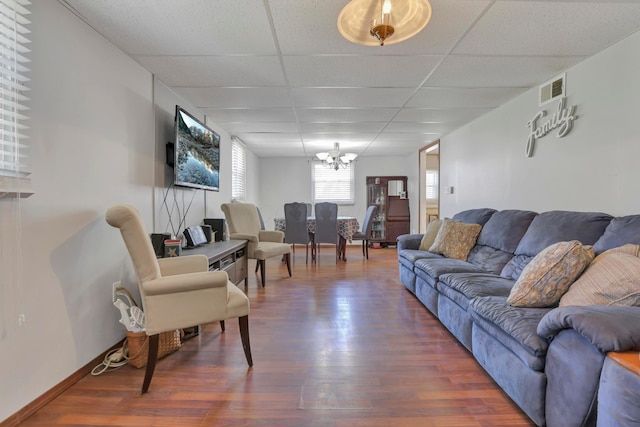 living room with a chandelier, baseboards, a drop ceiling, wood finished floors, and visible vents