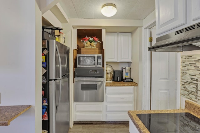kitchen with under cabinet range hood, white cabinetry, appliances with stainless steel finishes, and wood finished floors