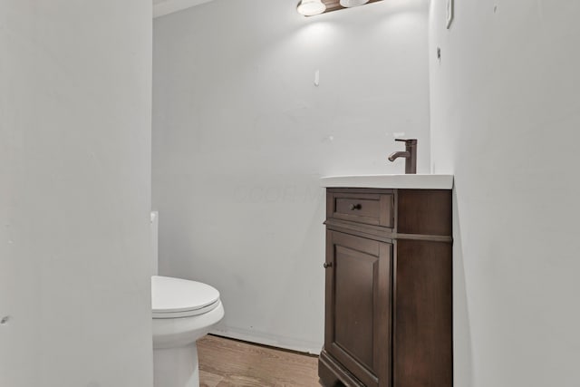 half bath with vanity, toilet, and wood finished floors
