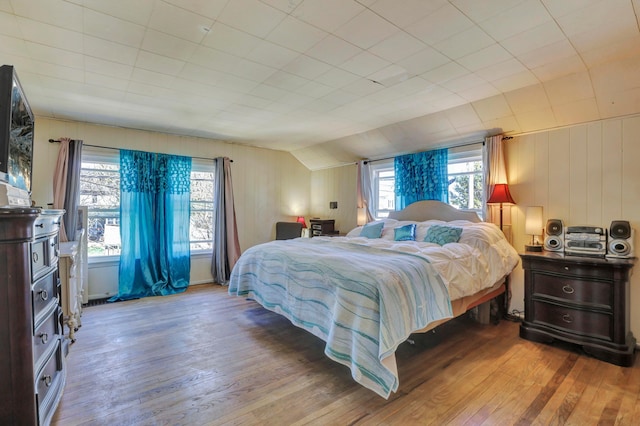 bedroom featuring multiple windows, vaulted ceiling, and hardwood / wood-style flooring