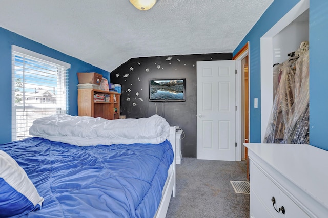 carpeted bedroom with vaulted ceiling, a textured ceiling, and visible vents