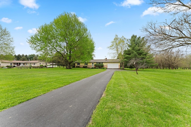 ranch-style house featuring an attached garage, driveway, and a front yard