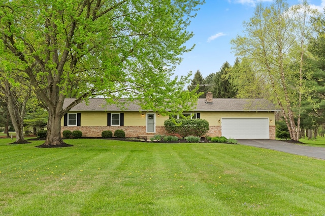 ranch-style house with a chimney, a front yard, a garage, brick siding, and aphalt driveway