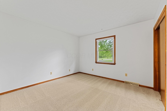 unfurnished bedroom with baseboards, light carpet, and visible vents