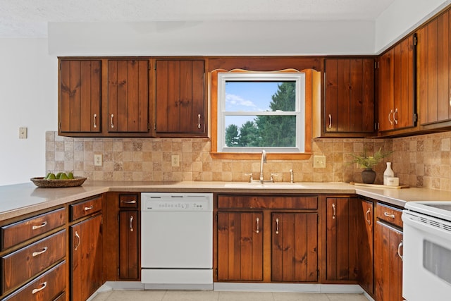 kitchen featuring a sink, decorative backsplash, white appliances, and light countertops