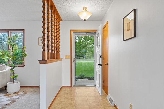 doorway to outside with visible vents, a textured ceiling, baseboards, and plenty of natural light