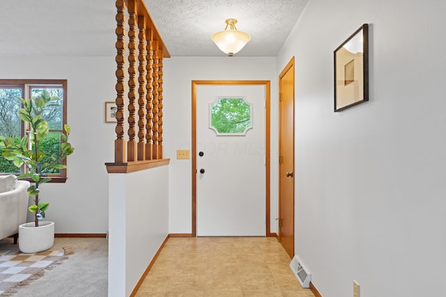 doorway with a textured ceiling, baseboards, and visible vents