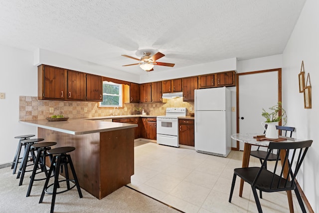 kitchen with white appliances, a peninsula, ceiling fan, and backsplash