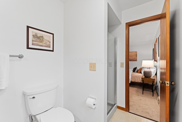 ensuite bathroom with baseboards, connected bathroom, a stall shower, and toilet