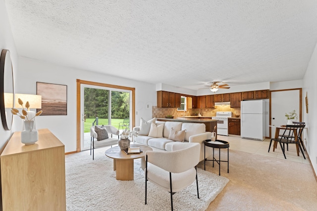 living area featuring a textured ceiling, ceiling fan, and light carpet