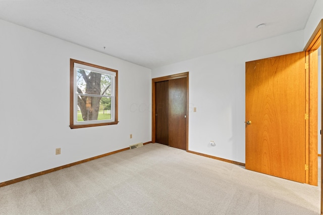 unfurnished bedroom with baseboards, visible vents, carpet, and a closet