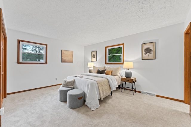 bedroom featuring baseboards, visible vents, a textured ceiling, and light colored carpet
