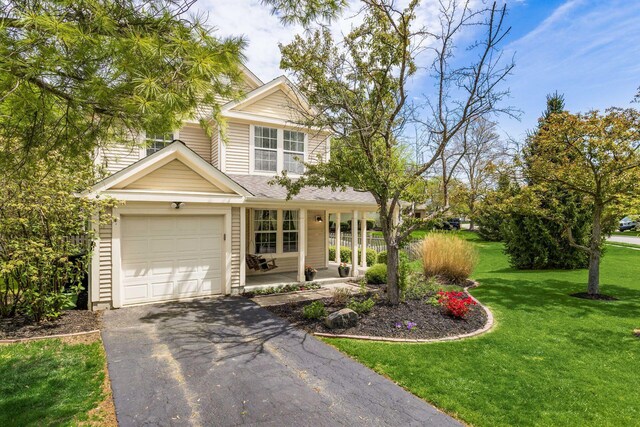 view of front of house with a garage, covered porch, driveway, and a front yard
