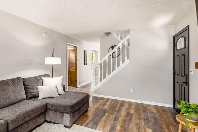 living area with visible vents, stairs, wood finished floors, baseboards, and a textured ceiling