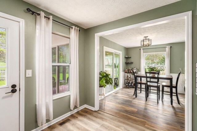 interior space with baseboards, a textured ceiling, visible vents, and wood finished floors