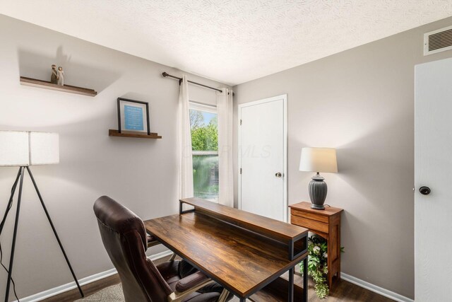 home office featuring visible vents, a textured ceiling, baseboards, and dark wood-style flooring