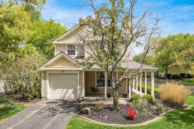 traditional home featuring a porch, a garage, fence, and aphalt driveway