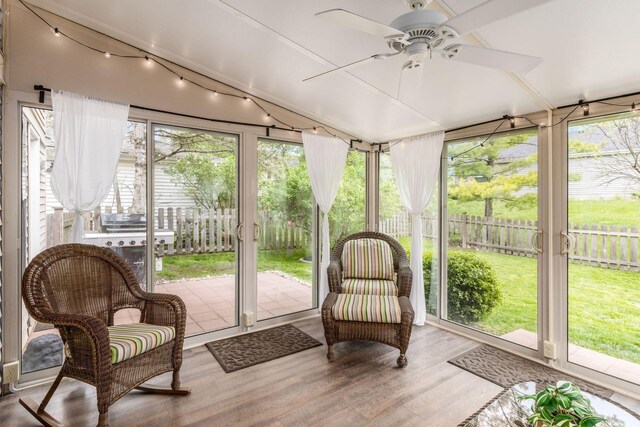 sunroom featuring a ceiling fan and wood finished floors