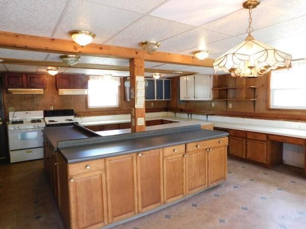 kitchen featuring open shelves, dark countertops, a center island, white gas range oven, and decorative light fixtures