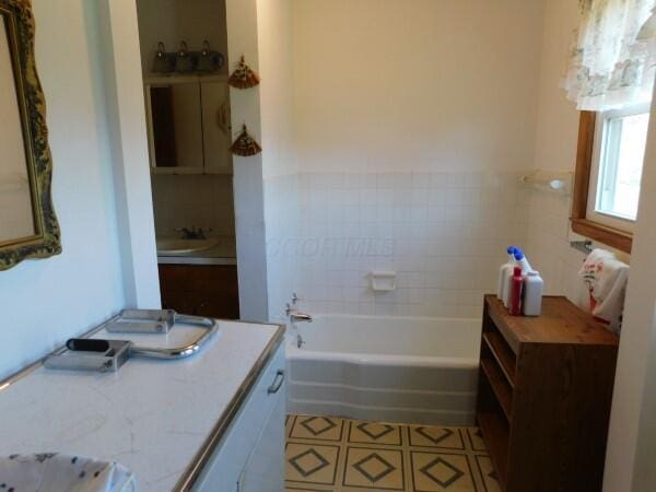 bathroom with a tub, vanity, and tile patterned flooring