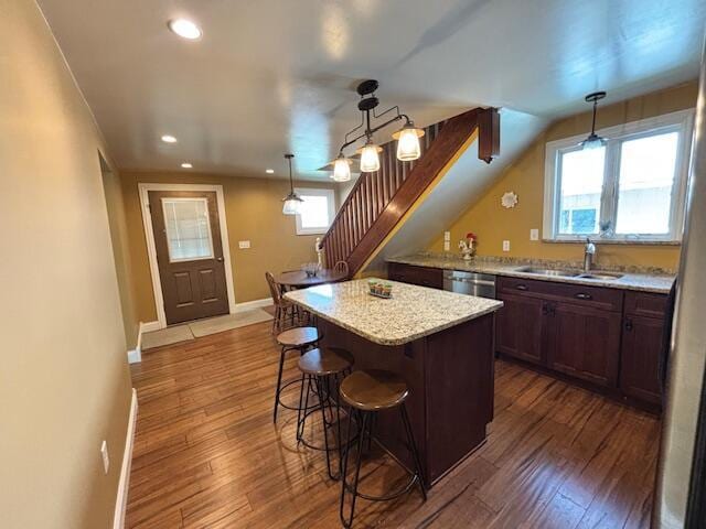 kitchen with a sink, a kitchen breakfast bar, recessed lighting, baseboards, and stainless steel dishwasher
