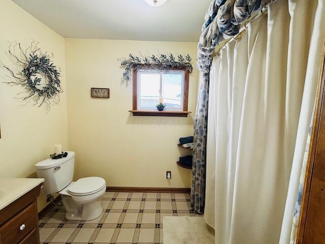 bathroom with vanity, baseboards, tile patterned floors, and toilet