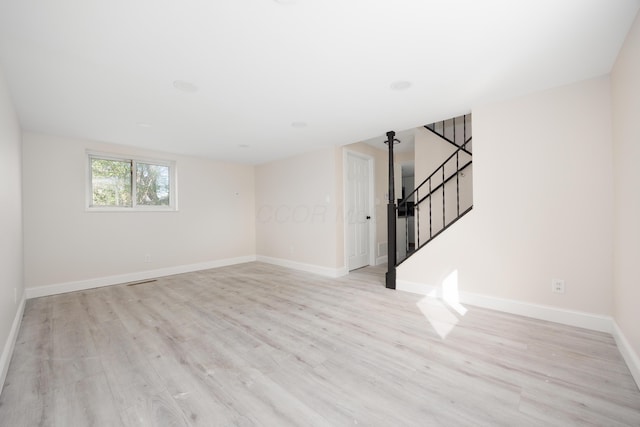 unfurnished living room with light wood-style floors, baseboards, and stairs