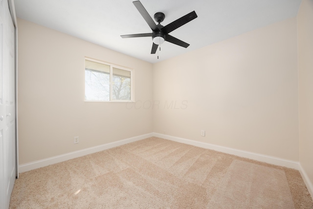 carpeted spare room with baseboards and a ceiling fan