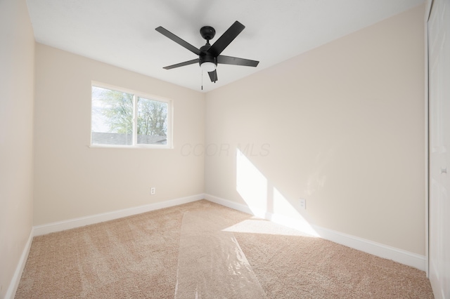spare room with baseboards, ceiling fan, and carpet