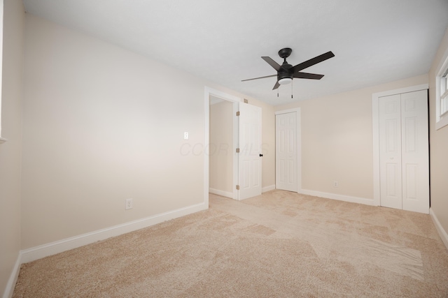 unfurnished bedroom with baseboards, a ceiling fan, two closets, and light colored carpet