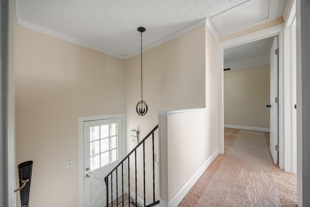 hall with carpet floors, baseboards, crown molding, and an upstairs landing